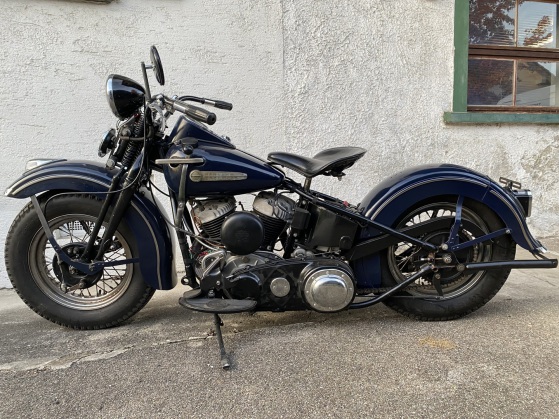 Dunkelblaue Harley mit tief gezogenen Schutzblechen und Solositz auf dem Hof