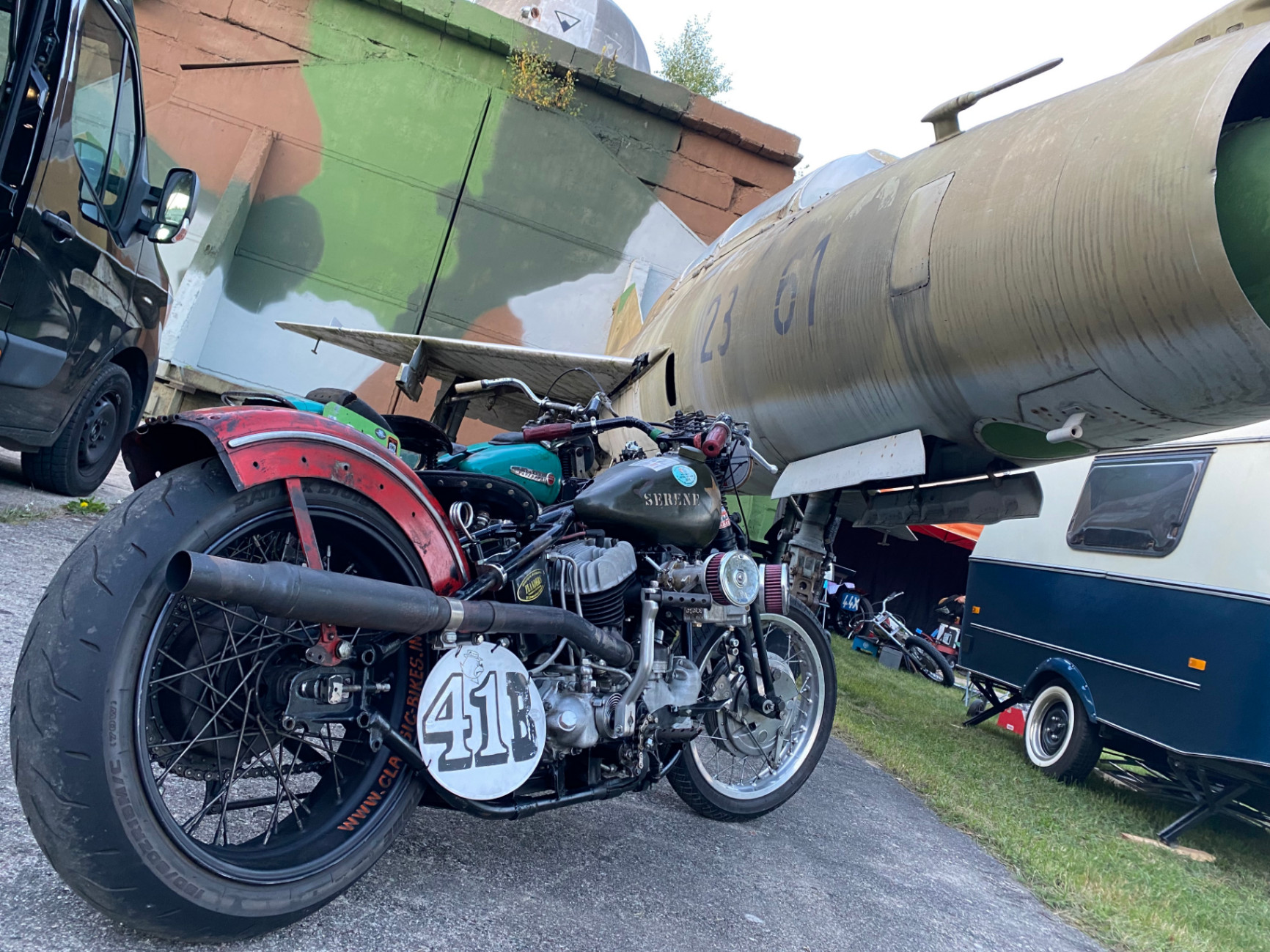 Schwarze Harley-Davidson mit Solositz und langem Fishtail-Auspuff vor einer weiß verputzten Werkstattwand